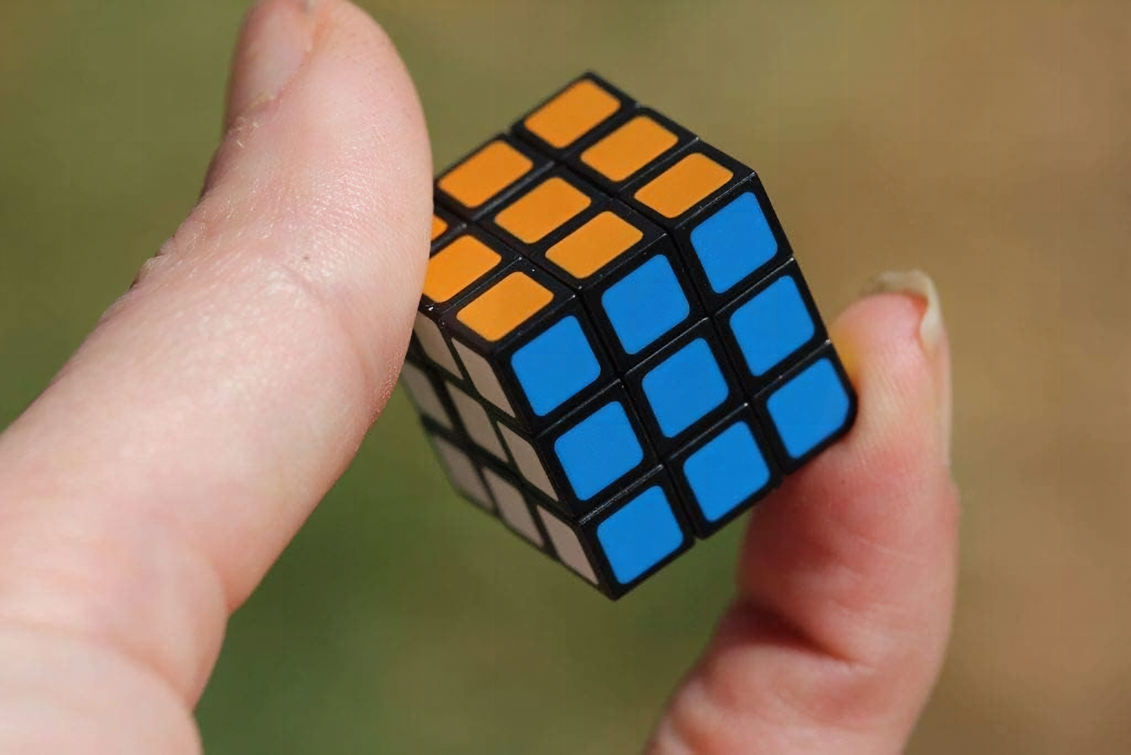 Extreme close-up of a tiny Rubik's cube with colorful stickers partially twisted, shallow focus