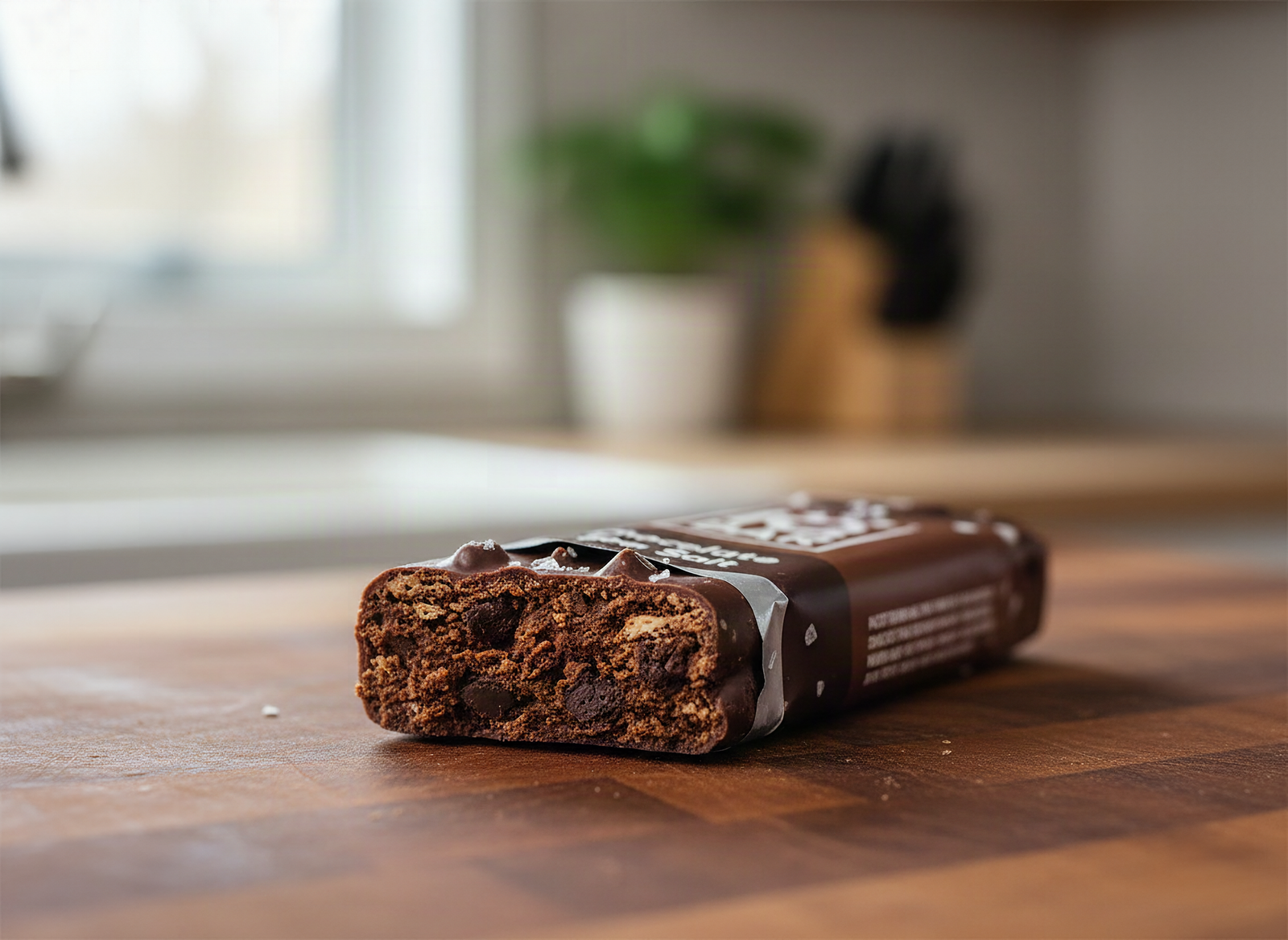 Close-up of a broken IQBAR chocolate bar showing dense plant-based texture and embedded chocolate chips