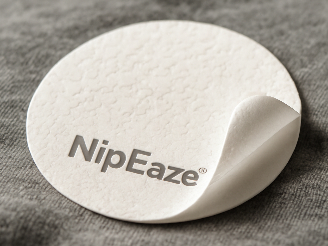 NipEaze nipple cover in extreme close-up on white cotton fabric, showing adhesive detail and protective surface