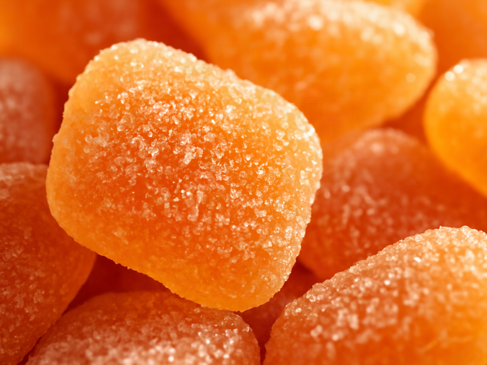 Macro shot of peach sour gummies with visible crystal texture and golden backlighting