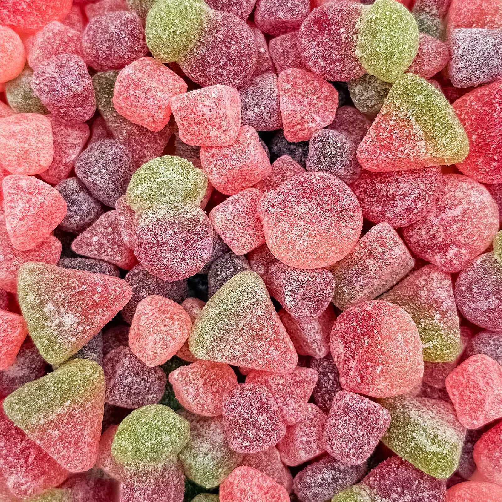 Macro close-up of colorful sour fruit jelly candies with translucent surfaces on a white plate
