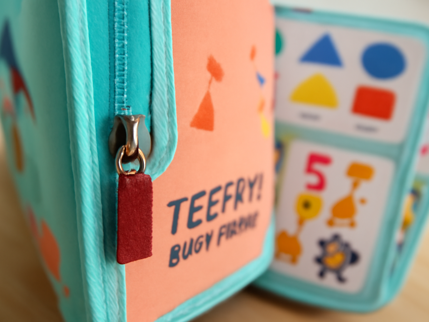Macro close-up of Teefrye busy board zipper detail with colorful activity panels visible in soft focus