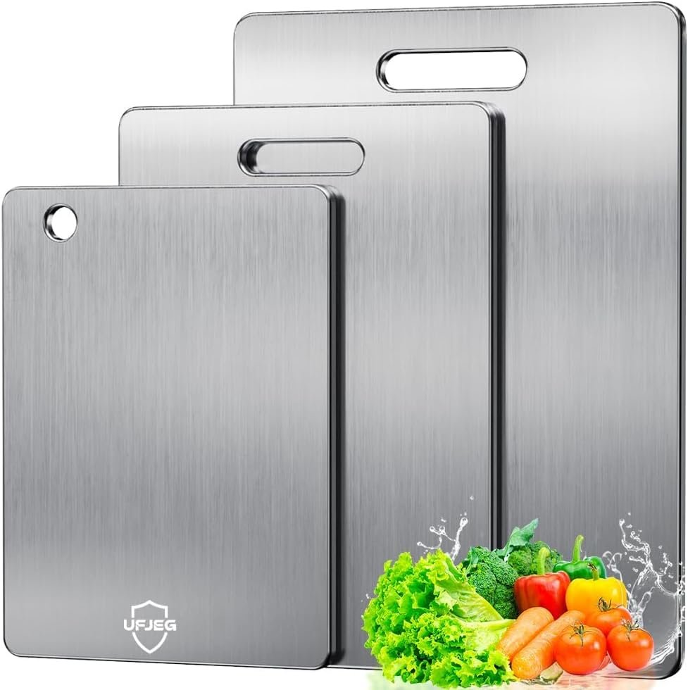 Three titanium cutting boards set up on an outdoor picnic table with fresh produce and camping gear