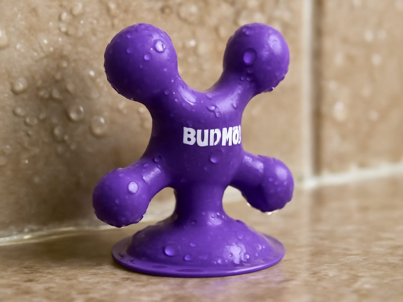 BUNMO bath toy's suction cup pressed firmly against wet tile, showing water droplets on the sealed surface