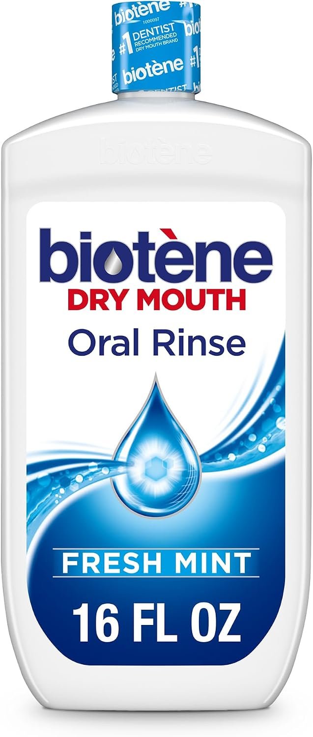 Biotene oral rinse bottle on a nightstand next to a water glass and tissues in a dimly lit bedroom