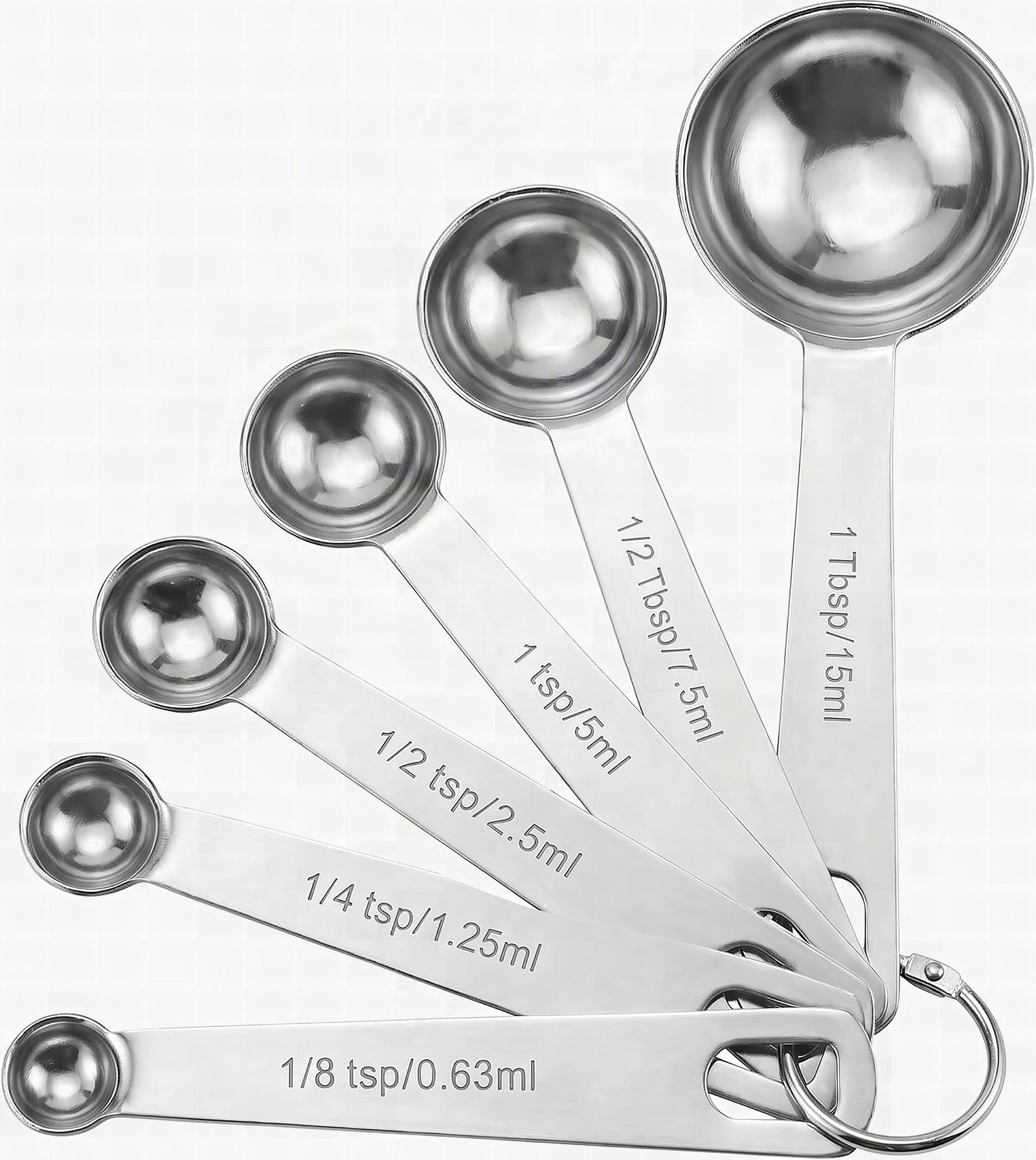 Six stainless steel measuring spoons fanned out in macro close-up with sunlight reflecting off polished metal